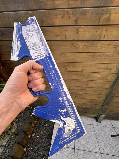 A hand holding a dirty painting ruler faintly reminiscent of the famous Klingon weapon.