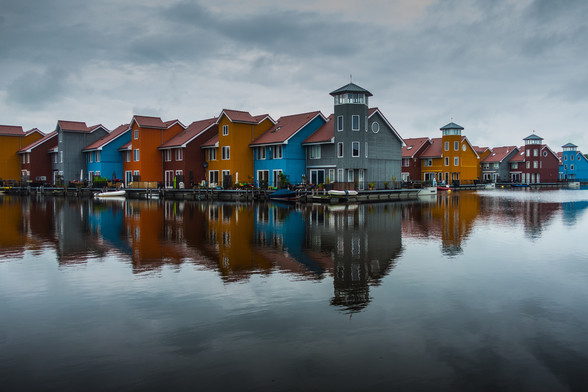 Colorful houses reflected in water under an overcast sky.