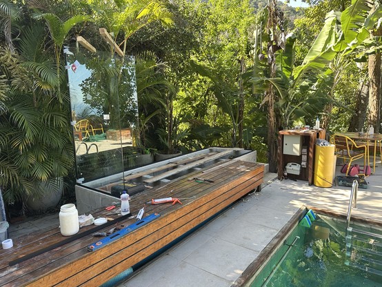 A concrete base behind a wooden bench holds two glass sheets in the corner