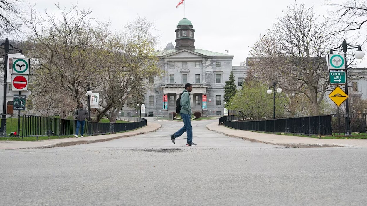 Une personne marche devant un grand bâtiment.