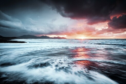 A dramatic winter sunset at Dinas Dinlle on the Gwynedd coast. Waves, clouds and a burst of sunset colours.