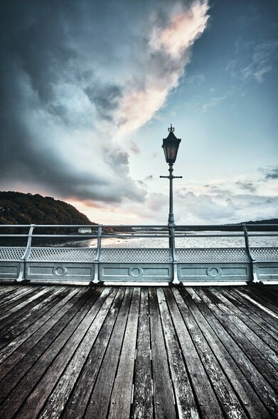 Sunset looking up the Menai Straits from Bangor pier. A lamppost points upwards towards a clear patch in the sky.