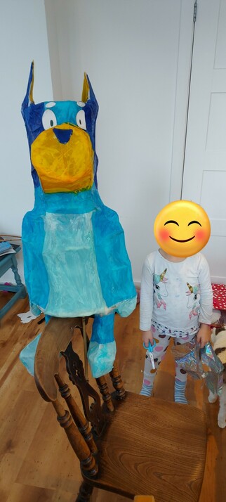 A hand made blue dog lantern next to a five year old girl. They are about the same size.