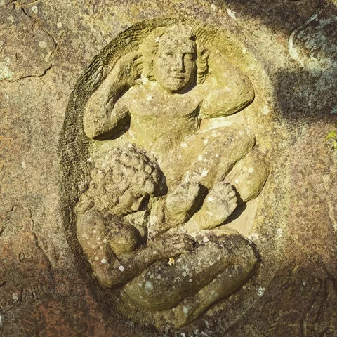 A faded inset stone carving of two people.