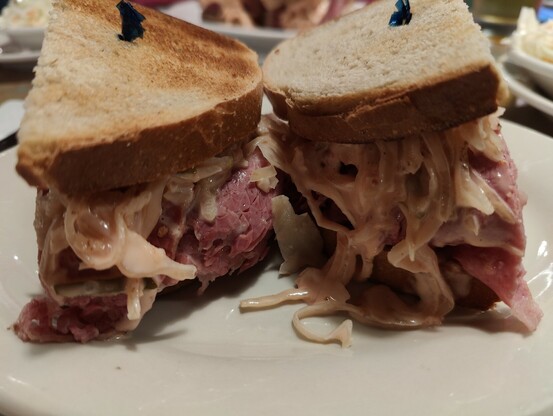 A Reuben Sandwich. A large quality of corned beef stuffed between 2 slices of toasted bread.