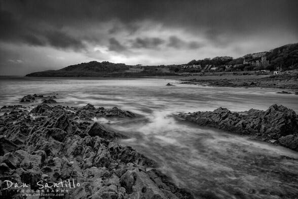 A moody black and white photo of Rotherslade at sunset
