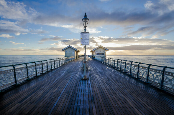 A symmetrical image looking down Penarth Pier just after sunrise.
