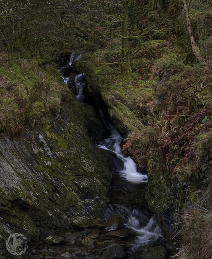 A small waterfall on a tree lined hillside in Morth Wales. Long exposure turns the water silky