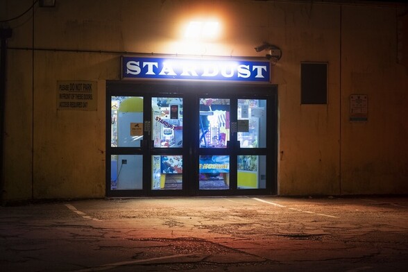 Side doors to an amusement arcade. Overhead light shining onto a car park at night.