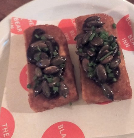 Two slices of fava bean panisse with a topping of smoky beetroot and pumpkin seeds on a side plate at the Black Bear, Usk.
