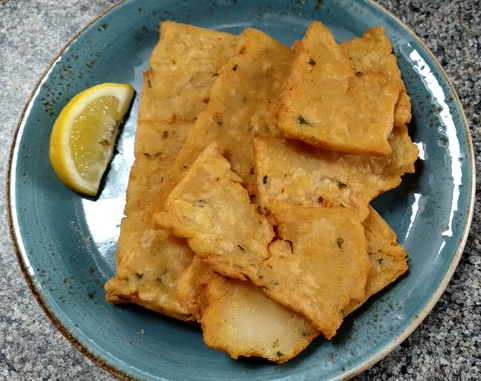 Several pieces of panelle from Pasta a Casa at Roath Market, plated with a wedge of lemon included.