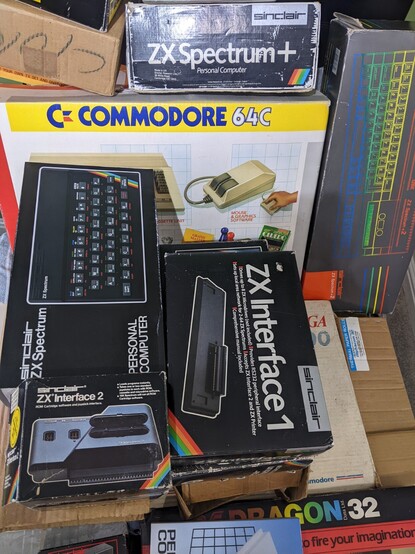 A collection of vintage boxed computers, including Commodore 64C, Sinclair ZX Spectrum, ZX Interface 1, ZX Interface 2, Amiga 500, Sinclair ZX Spectrum +2, Sinclair ZX Spectrum+ and more.