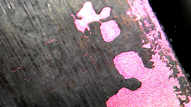 USB microscope image of an AMD Athlon laptop CPU, without the usual lid typical of a desktop CPU. The die can be seen directly (pink), with some old thermal paste stuck to it (black).