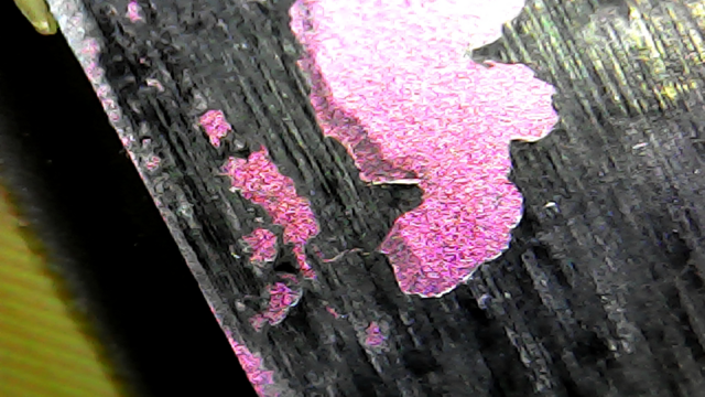 USB microscope image of an AMD Athlon laptop CPU, without the usual lid typical of a desktop CPU. The die can be seen directly (pink), with some old thermal paste stuck to it (black).