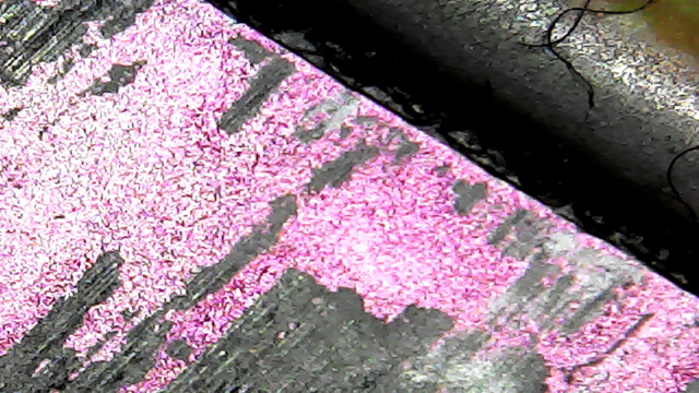 USB microscope image of an AMD Athlon laptop CPU, without the usual lid typical of a desktop CPU. The die can be seen directly (pink), with some old thermal paste stuck to it (black).
