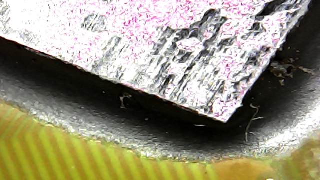 USB microscope image of an AMD Athlon laptop CPU, without the usual lid typical of a desktop CPU. The die can be seen directly (pink), with some old thermal paste stuck to it (black).