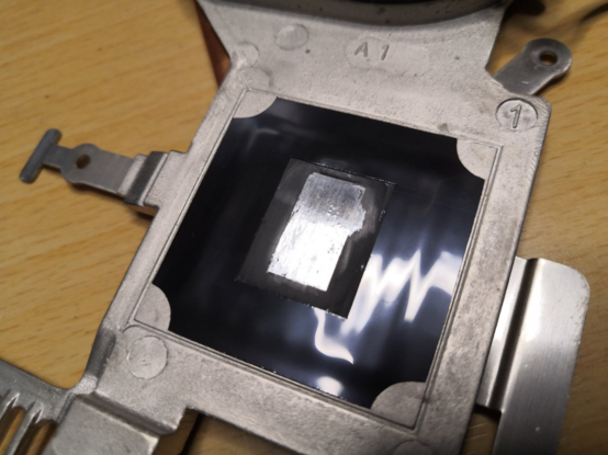 Underside of a laptop heatsink (the part in contact with the CPU die) after partial cleaning. It's clearer now that the silver rectangular part was the only part in contact with the CPU die, and untouched black thermal paste surrounds it.