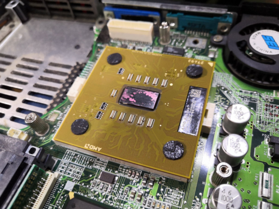 Before: AMD Athlon laptop CPU with die visible (pink) and old thermal paste (black).