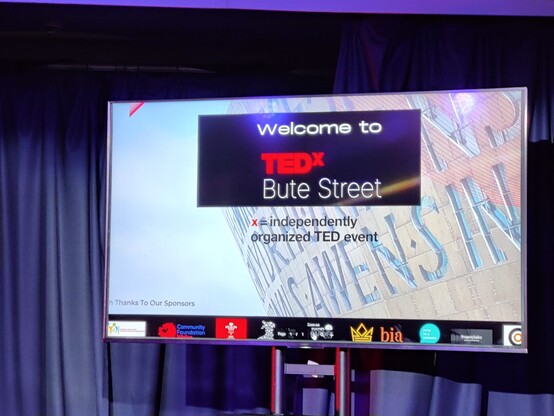 A large screen displays the message, Welcome to TEDx Bute Street. x = independently organised TED event