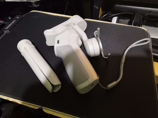 DJI Osmo Mobile 4 phone gimbal (pistol-grip joystick-shaped motorised mobile phone holder/stabiliser) on a table.