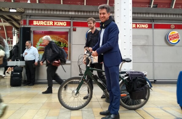 A man in a blue suit stands with a bicycle in a railway station