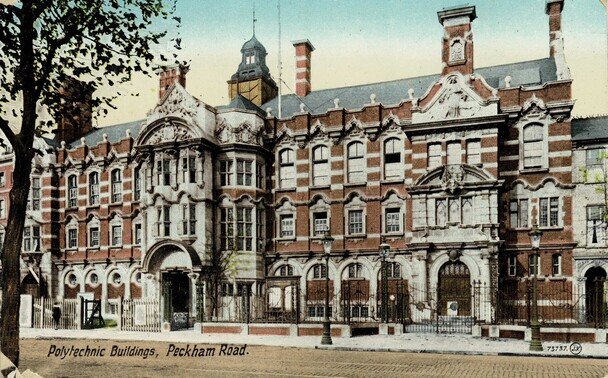 Old postcard of the Camberwell School of Arts and Crafts. The colour card in landscape orientation shows a Victorian brick building, with facings of white stone. It is three floors high, with a slate roof, many chimneys, ornate windows and a grand central door. It is on an empty  street. At the foot of the card is printed in black "Polytechnic buildings, Peckham Road"