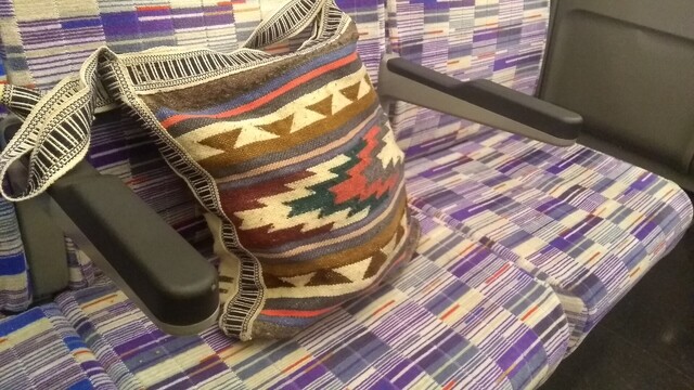A patterned cloth bag, contrasting badly with the train seat cloth