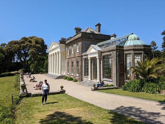 A picture taken at an angle of a grand stately home with a seating area in front of it 