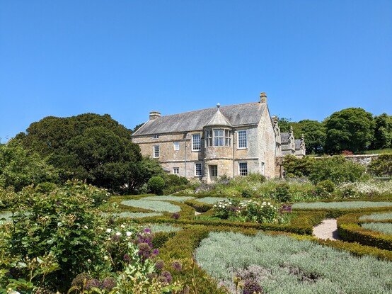 An old home which is now a national trust property. In front of it are gardens