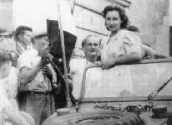 A young woman in a Jeep surrounded by people 