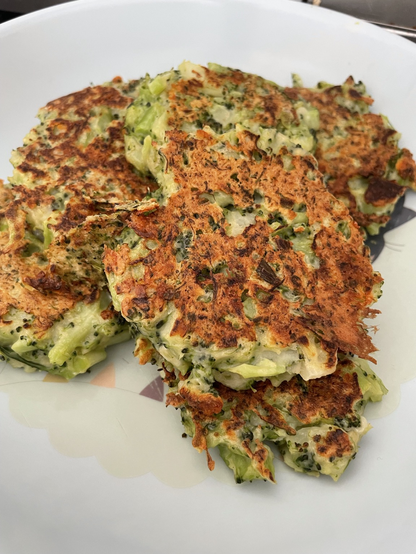 A plate of broccoli and pea fritters. The fritters are pan-fried so are golden brown with a good crust where the cheese has melted