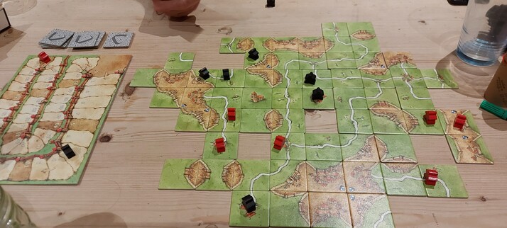 A woker placement game with a load of square tiles that end up forming a larger map. On it are the workers you place, in our case black and red meeples. There is also a scoreboard.