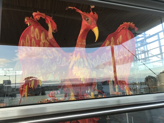 A photo of a large red model bird behind glass.