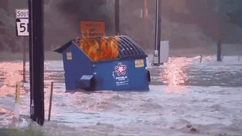 a dumpster floating through a flood whilst on fire