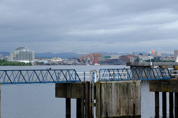 Looking across Cardiff Bay from Penarth Marina. In the foreground are walkways to morning stations, whilst in the background you can see the St David’s hotel, the Wales Millenium Centre theatre and the Senedd, the home of the Welsh Government. The hills beyond Cardiff and towards Newport are distant shadows 