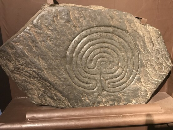 A carving of a circular labyrinth on a rock.