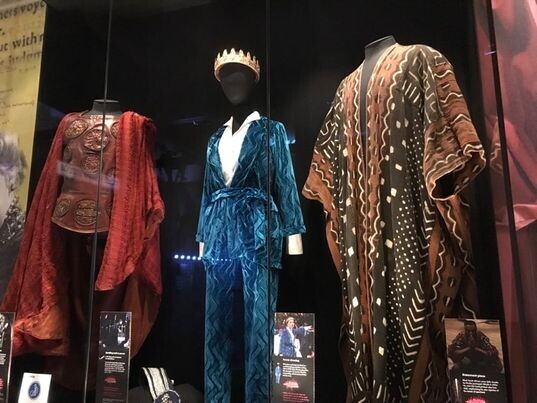 Three mannequins wearing theatre costumes displayed behind glass.
