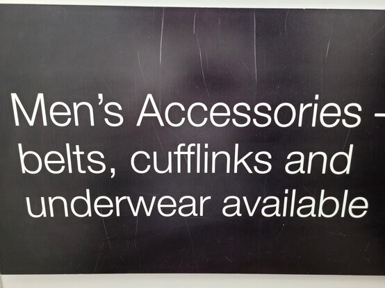 A sign in a menswear shop changing room that reads:"Men’s Accessories - belts, cufflinks and underwear available".