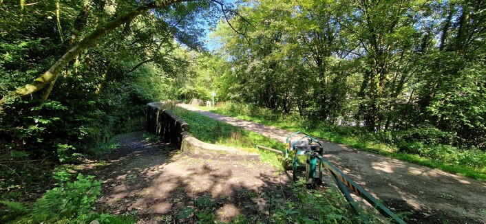 The location of the old village train station. You can make out where the two platforms used to be. A wide sloping path to the left takes you down to the village from the platform under a tunnel. Everything is beautifully surrounded by trees.