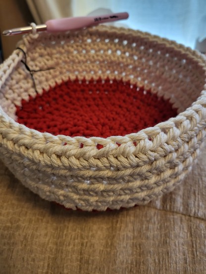 Macramé basket with a red base and cream walls, about a third crocheted so far. 