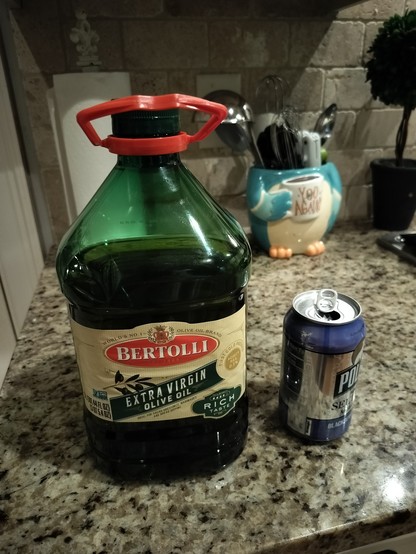 Big ass 100+ oz jug of olive oil beside a 12 oz can 