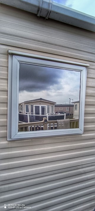 Reflection in the Caravan Window of the Clouds and the other Caravans