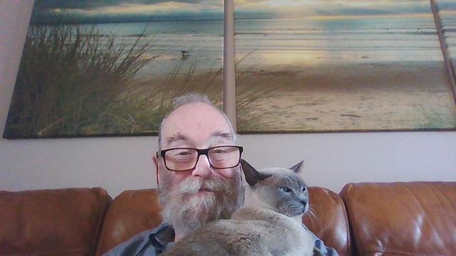 Selfie taken with Chromebook, showing me, with a cat sat on me. I'm the one with the beard and glasses.