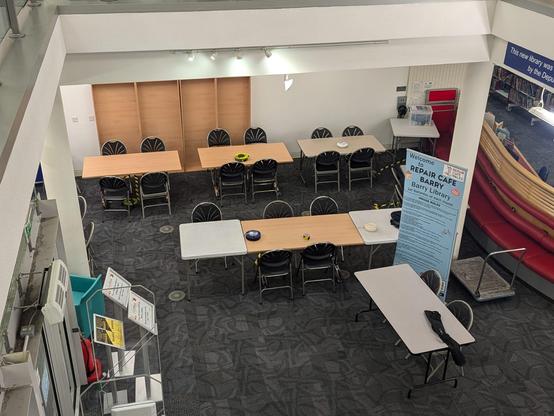 A corner of Barry library set up with tables and chairs and the Repair Café Barry sign.