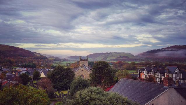 Swirly clouds over the autumnal valley. Some slight token mist covers the hills on either side.