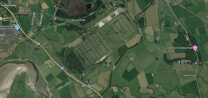 A screenshot from Google maps, showing an aerial photo of an area near Gretna, with a rectangular complex with a very regular pattern of small rectangular structures each surrounded by grass. 