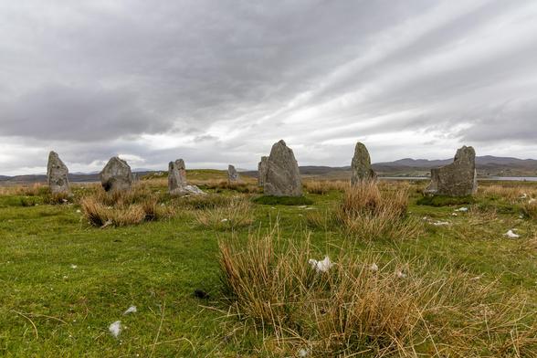 Photograph of Steinacleit stone circle and cairn, shwing the stones on a bleak moor with a very grey sky