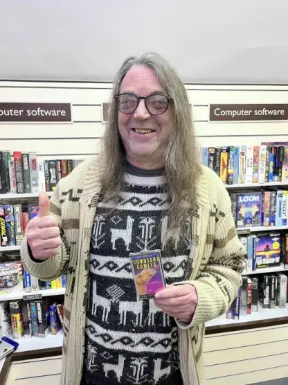 There's even a reproduction of the software area of a WH Smiths. Here I am standing in front of shelves of software and I am holding a copy of the Mastertronic re-release of Attack of the Mutant Camels for the 8-bit Atari.