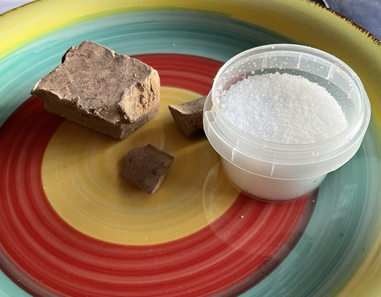 Lump of cacao and small pot of truvia sweetener on a colourful plate 
