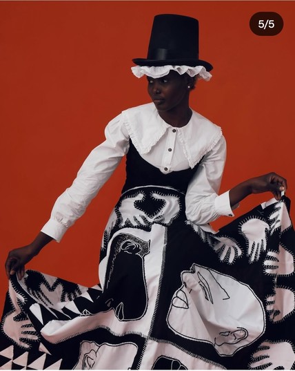 Patchwork quilt (black and white hands and faces)  worn by a stunning African woman wearing iconic Welsh hat 